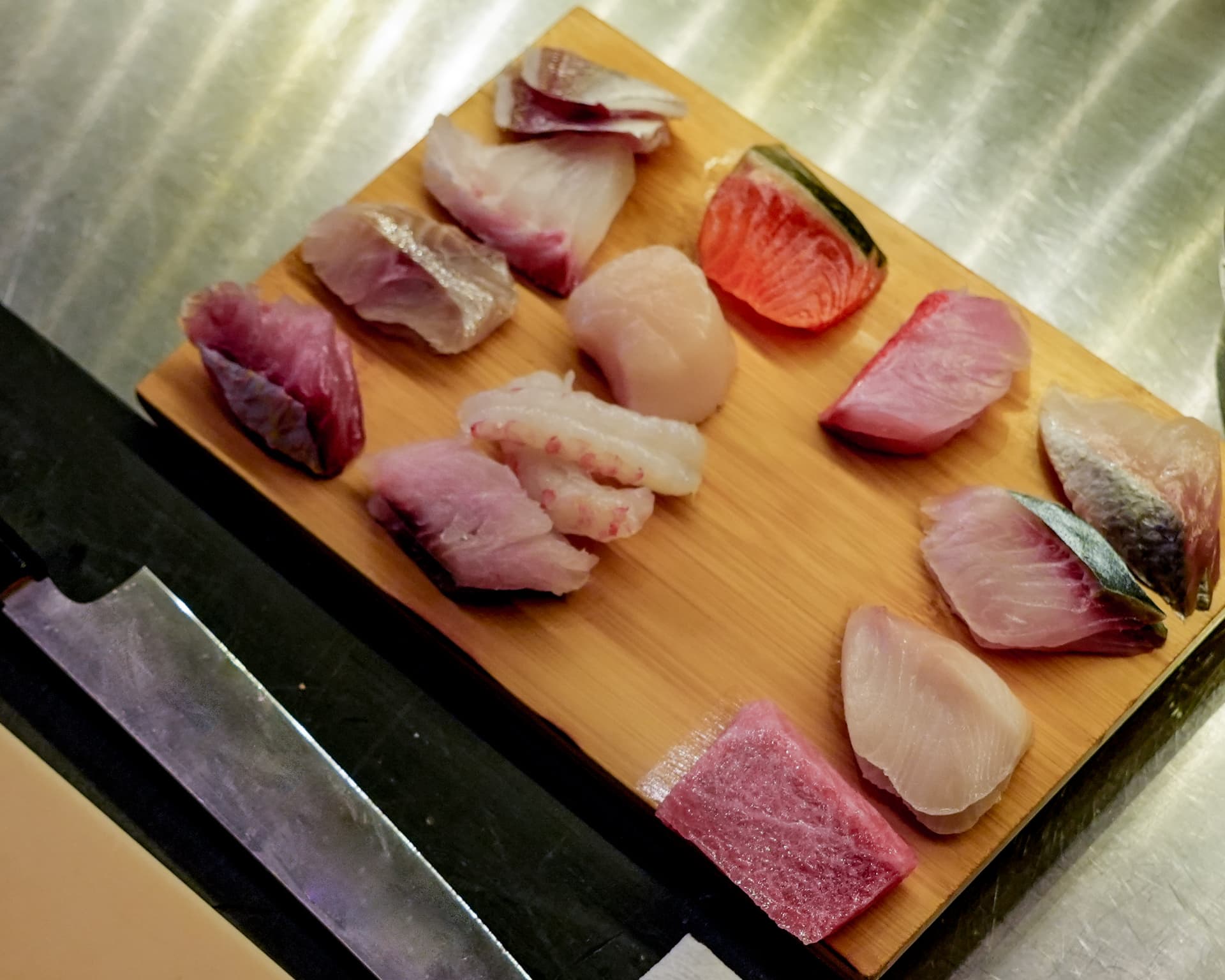 Assorted cuts of raw fish arranged on a wooden board at the Mido counter