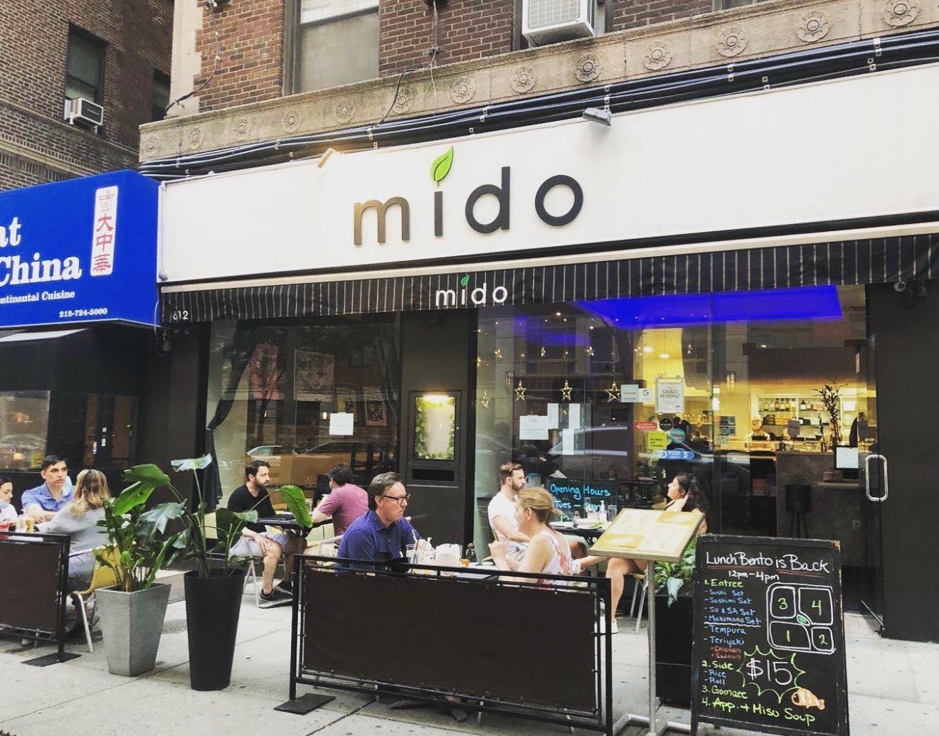 The Mido Japanese Upper West Side storefront on Amsterdam Avenue, with sidewalk seating under a striped awning