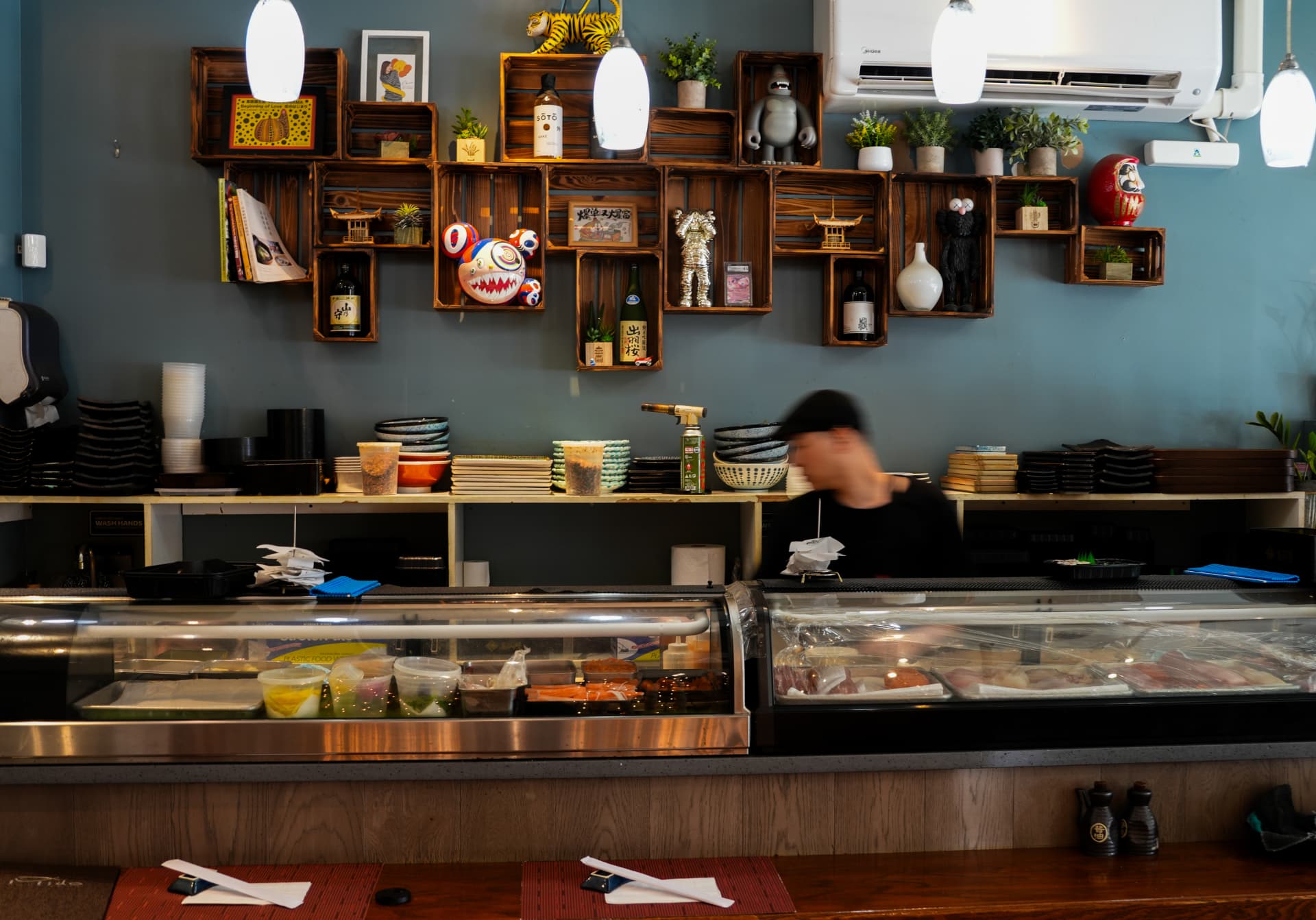 The sushi counter at Mido Japanese Upper West Side, with a refrigerated display of fish and a chef at work